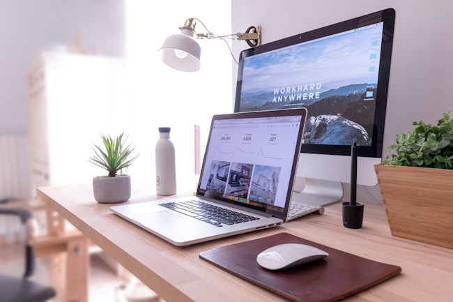 A desk with a laptop and creative materials